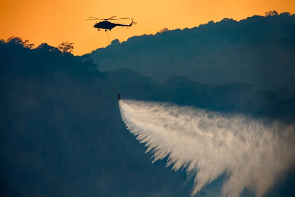 Helicopter dumping water on forest fire