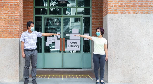 Asian middle aged people wearing mask and keep social distancing to avoid the spread of COVID-19