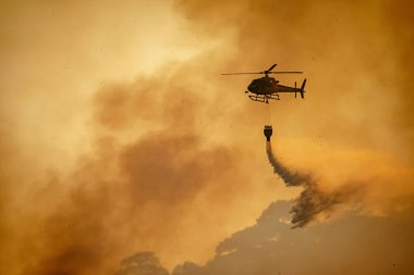 Helikopter orman yangınına su döküyor.