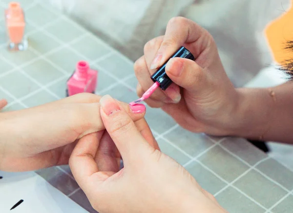 One girl paint nails with pink nail polish
