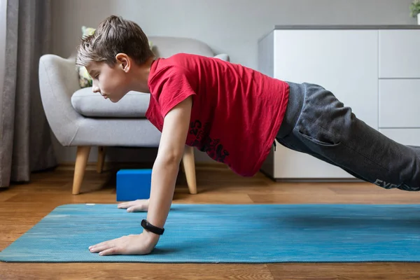 Small boy on yoga mat at home holding plank pose — Stock Photo, Image