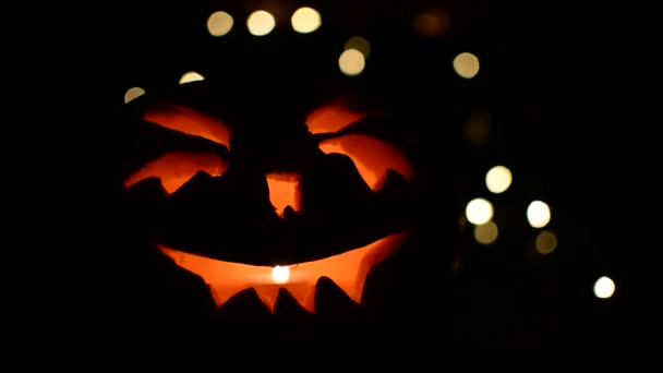 Rosto esculpido de abóbora brilhando no Halloween no fundo de luz bokeh — Vídeo de Stock