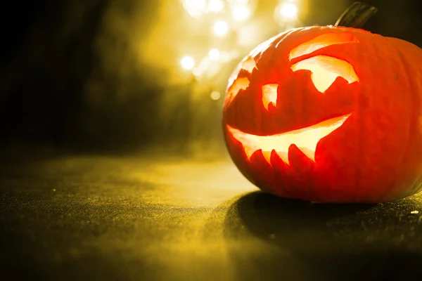 Snidade ansikte av pumpa glödande på Halloween på gula bokeh ljus bakgrund — Stockfoto