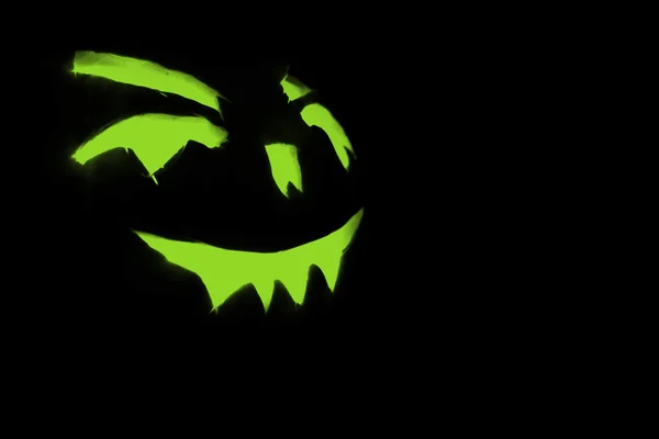Groene gesneden gezicht van de pompoen gloeien op Halloween zwarte achtergrond — Stockfoto