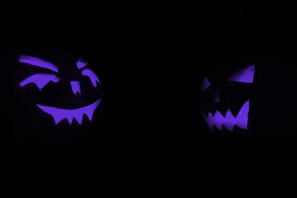 Dois azul esculpido rosto de abóbora brilhando no Halloween fundo preto — Fotografia de Stock