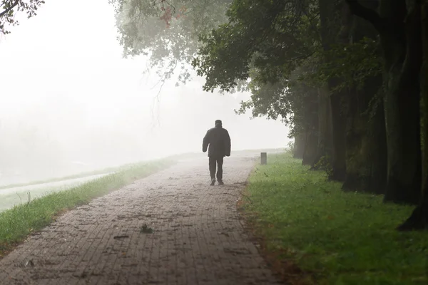 Alter Mann geht in den Nebel — Stockfoto