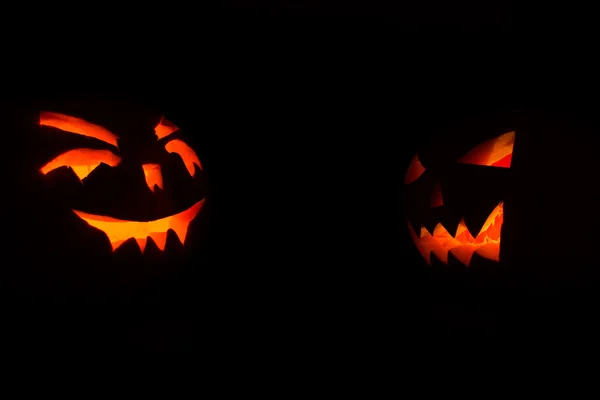 Halloween-Kürbisse mit Kerzen drinnen auf schwarzem Hintergrund — Stockfoto