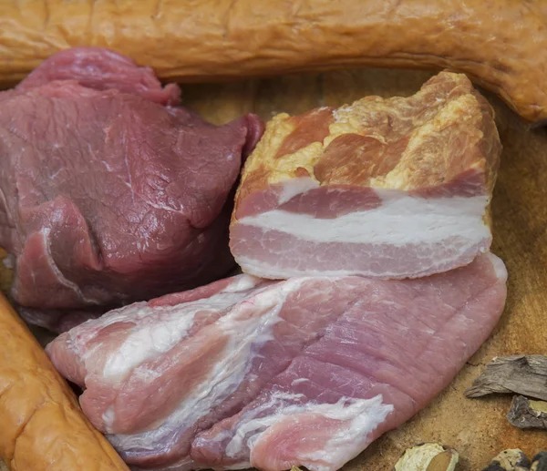 Manzo crudo, pancetta, maiale, salsiccia e funghi su fondo rustico di legno — Foto Stock