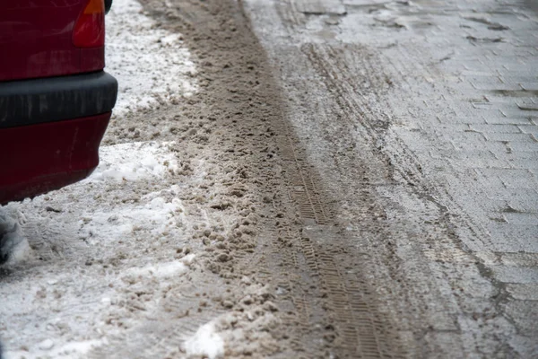 Pistas de neumáticos en la nieve derretida en el camino de asfalto — Foto de Stock