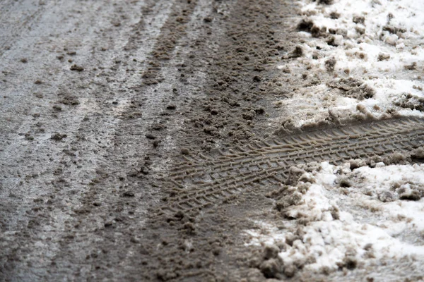 Stopy pneumatik v tavícím sněhu na asfaltové cestě — Stock fotografie