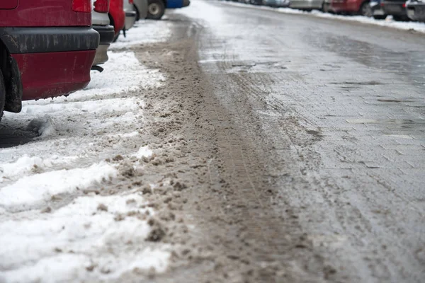 Pistas de neumáticos en la nieve derretida en el camino de asfalto — Foto de Stock