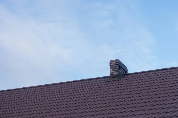 Taktekking med keramisk fliseskorstein mot blå himmel – stockfoto