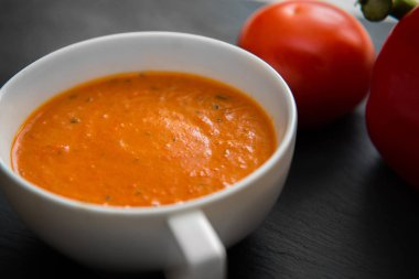 Közlenmiş biber ve domates siyah plaka üzerinde krem çorbası