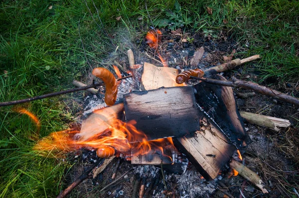 Pølse på pind, pejs på campingpladsen - Stock-foto