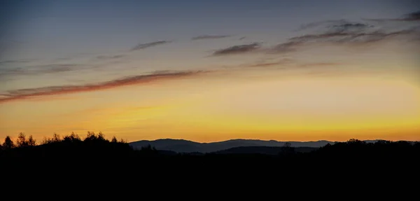 Восход солнца на лугу с холмами на заднем плане — стоковое фото