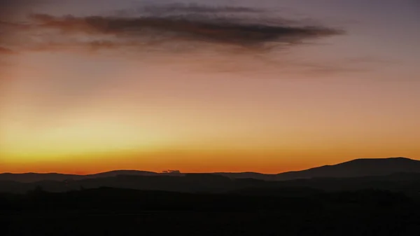 Восход солнца на лугу с холмами на заднем плане — стоковое фото