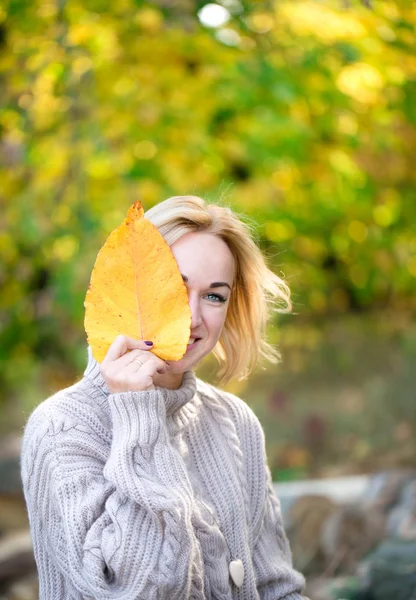 Mulher sorridente com folha amarela — Fotografia de Stock