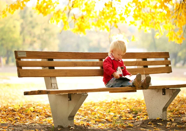 Dziecko, siedząc na ławce i czytanie książki — Zdjęcie stockowe