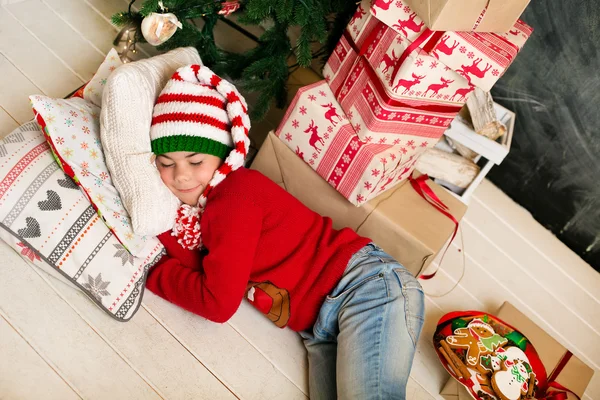 Junge ruht sich unterm Weihnachtsbaum aus — Stockfoto