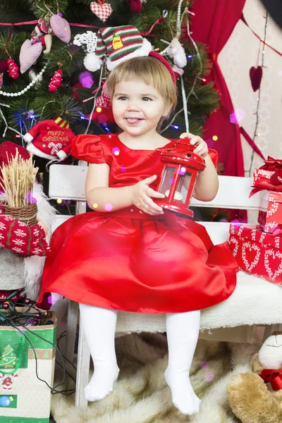 Kırmızı Noel Baba şapkalı küçük tatlı kız yeni yıl ağacı süslüyor. — Stok fotoğraf