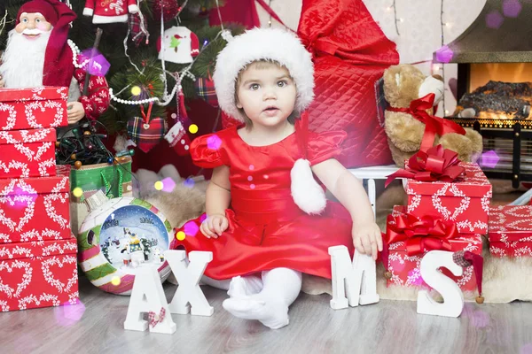 Little cute girl in red santa hat decorating new year tree — Stock Photo, Image