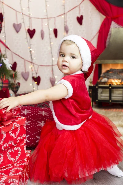 Liten söt flicka i röd tomte hatt dekorera nytt år träd — Stockfoto