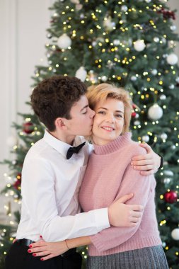 Anne ve oğlu Noel ağacını süslüyor. Anne ve oğul birbirlerine sarılırlar.