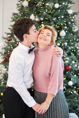 Anne ve oğlu Noel ağacını süslüyor. Anne ve oğul birbirlerine sarılırlar.