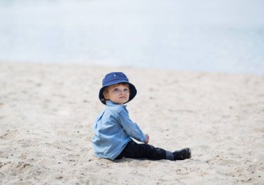 Mavi şapkalı gülümseyen kıvırcık bebek parkta oynar