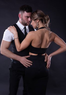 Gece elbisesi içindeki seksi kız ona nazikçe sarılan sevgili erkeğinin gözlerinin içine bakar.