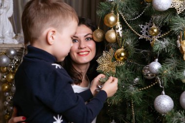 Oğluyla mutlu anne Noel ağacını süslüyor.
