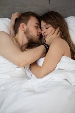 Sarılma ve öpüşme kapalı bir genç sevgili çift evde yatakta yatıyor.