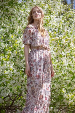 Young beautiful blonde in a blooming garden.