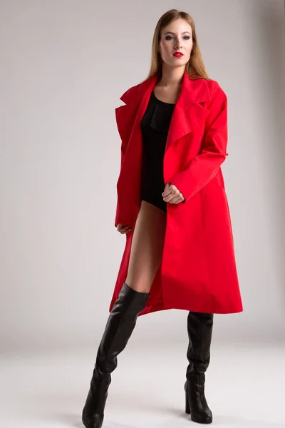 若いですセクシーな女性モデルと長い髪で明るい赤のレインコートと黒のボディスーツ 隔離された背景の肖像画 — ストック写真