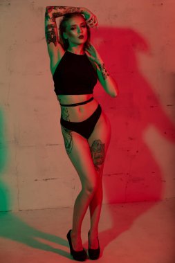 Siyah iç çamaşırlı seksi sarışın kadın. Yüksek topuklu uzun bacakları var.