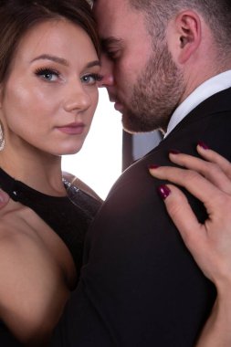 Stüdyoda arka planda sarılan zarif genç çift, yakın plan portresi.