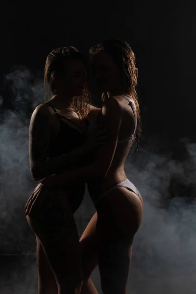 아름다운 레즈비언 여성들이 부드러운 포옹을 있습니다 어두운 방에서 조명을 연기를 — 스톡 사진