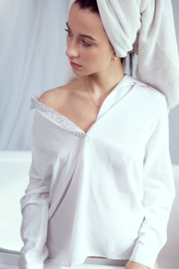 Beyaz pamuklu bir bluzla duştan sonra seksi bir kız ve kafasında bir havlu var.