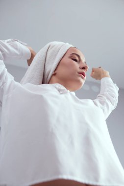 Beyaz, gevşek bir bluzla duştan ve kafasında havluyla çıkan seksi kız ellerini güzelce kaldırdı.