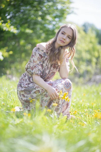 一个迷人的女孩在想一个阳光灿烂的日子 她坐在公园的草坪上 — 图库照片