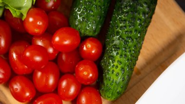 Taze lezzetli sebzeler: vişneli domates, salatalık turşusu ve çiğ taneli marul yaprakları. Sağlıklı beslenme kavramı.