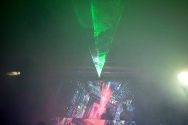 Yumuşak odak, gece diskosunda sigara içmek, canlı sahne, Kemer 'deki Club Phaselis Rose Oteli' nde neon ışıkları ve ışık huzmeleri, Türkiye 'nin yönetmen ve animasyoncuları, Tekirov' da şenlikli bir akşam.