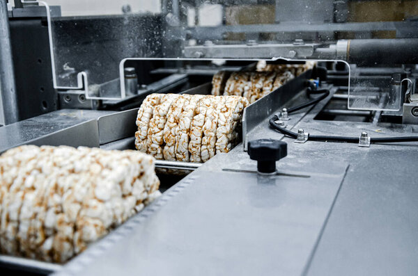 конвейер автоматический для производства полезного цельнозернового экструдера хрустящего хлеба. упаковка органических многоячменных брикетов с хрустящим хлебом на заводе
