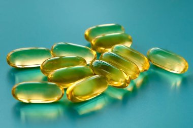 Mavi arka planda bir avuç dolusu omega 3 kapsülü 