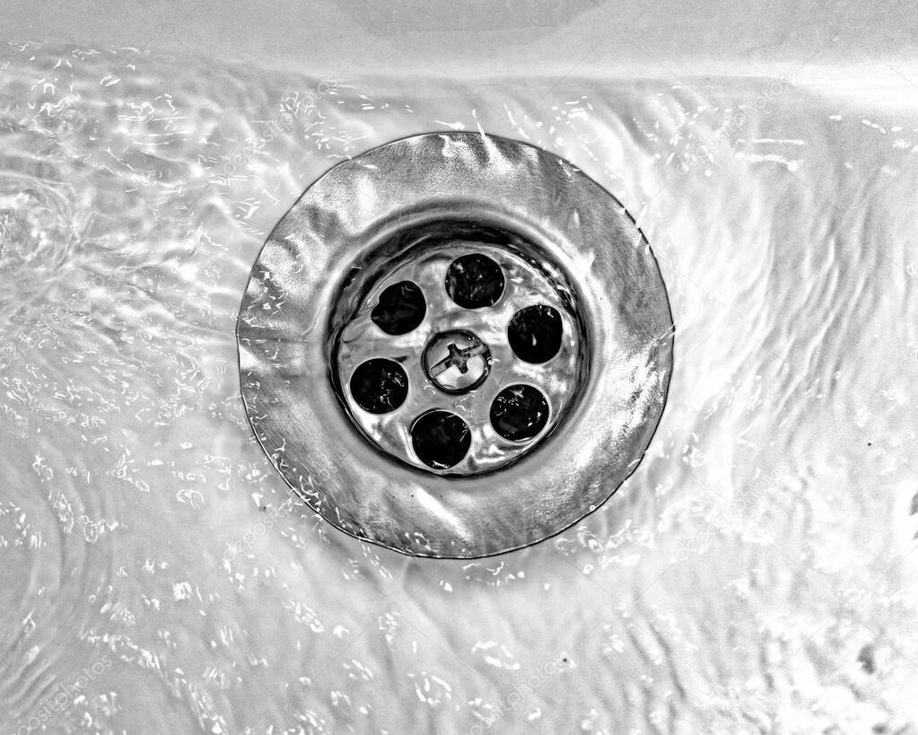 Draining water with a stainless steel grate in an old, long-used bathroom sink