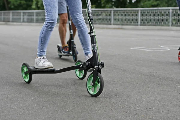 Flickan i parken på en trehjulig scooter — Stockfoto