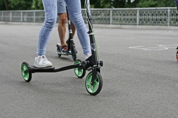 Fille dans le parc sur un scooter à trois roues — Photo