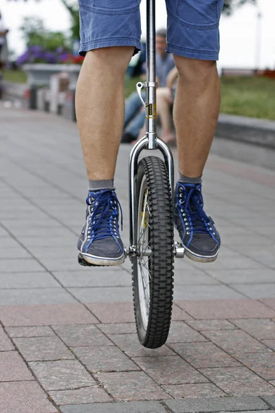 Un hombre mantiene su equilibrio en un monociclo — Foto de Stock