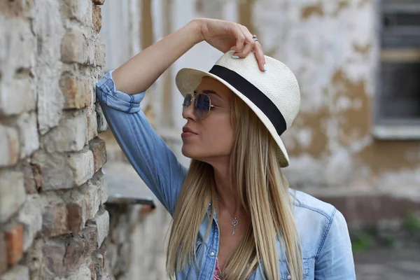 Girl in a hat near a brick wall — Stock Photo, Image