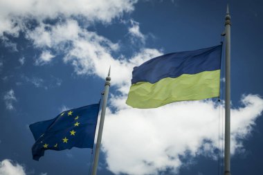 Avrupa ve Ukrayna bayrağı üzerinde mavi gökyüzüne karşı bayrak direkleri